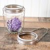 Glass jar with purple flowers and metal chain on a wooden surface