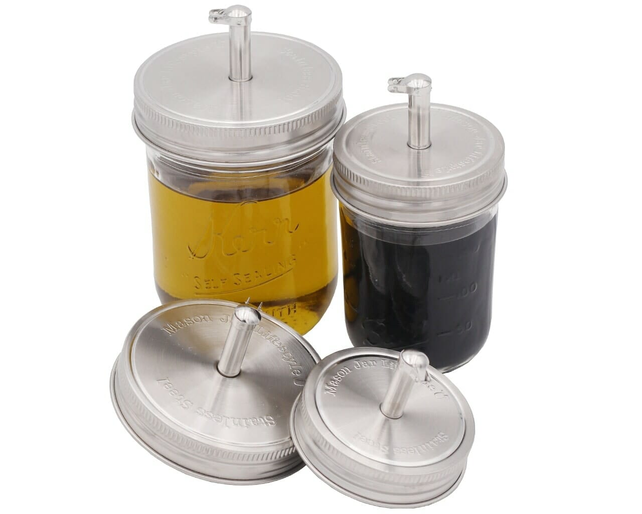 Two jars with silver lids and straws, one containing a yellow liquid and the other a dark liquid, on a white background.