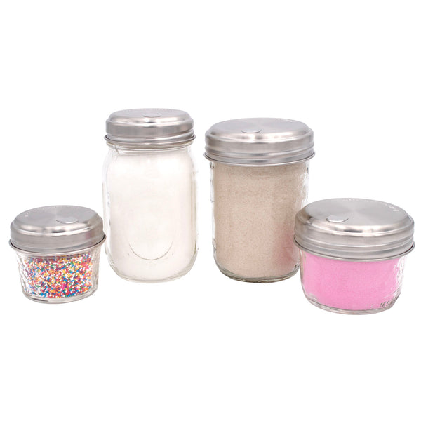 Set of four glass jars with metal lids, each containing different contents on a white background. Transform your Mason jars with the Sugar Dispensing Stainless Steel Lids at Clozist. Rust-resistant, food-safe, and dishwasher safe. A durable 2-pack designed for easy pouring and sustainable kitchen organization. The perfect green gift for bakers and coffee lovers!