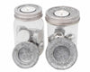 Two clear jars with metal lids containing tea lights on a white background