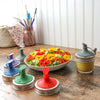 Colorful jar lids on a wooden surface with a bowl of salad in the background. Transform your Mason jars with the Silicone Oil Cruet Pour Lid at Clozist. Enjoy mess-free, non-toxic pouring for oils and dressings. Durable, dishwasher safe, and eco-friendly. The perfect sustainable gift for an organized, plastic-free kitchen!