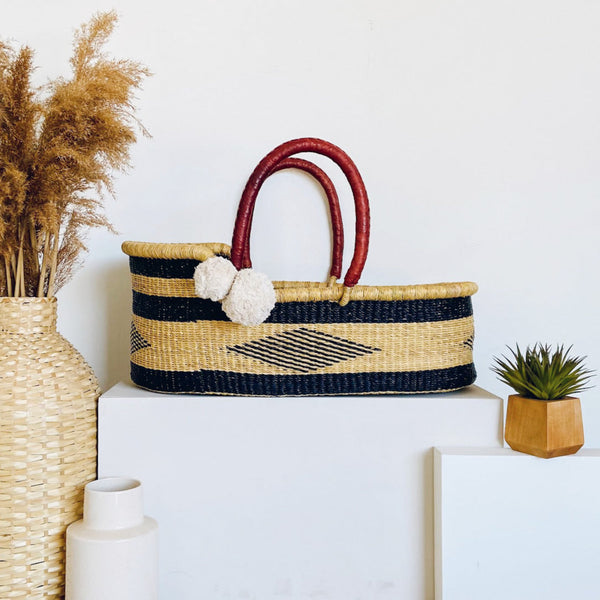 Woven basket with red handles on a white surface with decorative items.