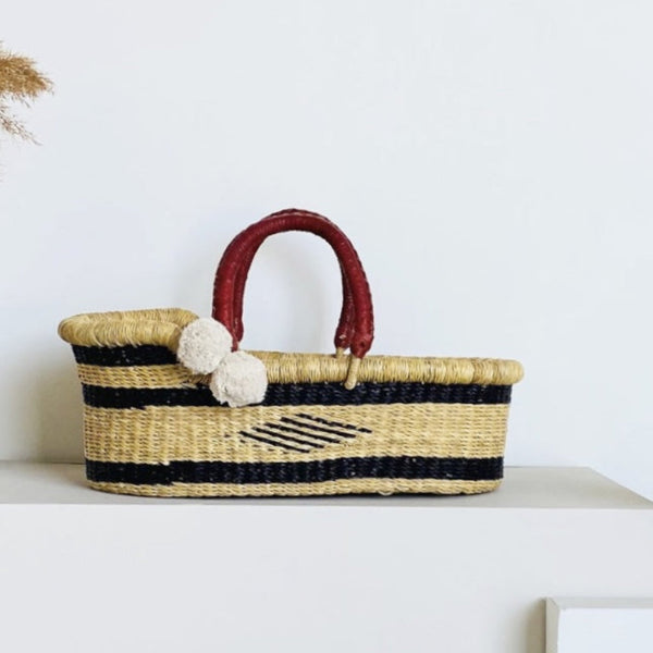 Plum+Sparrow Meadow Mini Moses Basket handwoven from elephant grass with navy blue hand-dyed tones and leather accents, made in Ghana