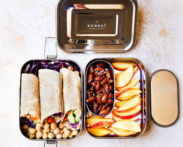 Metal lunch box with compartments containing wraps, fruits, and nuts, branded 'ecozoi'.