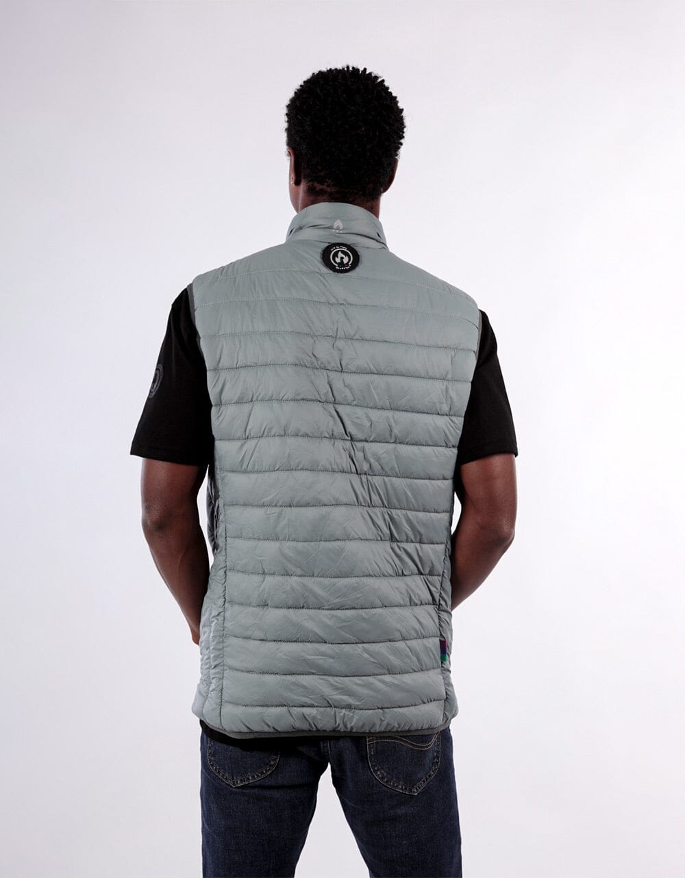 Person wearing a gray puffer vest on a white background