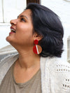 Close-up of mod red resin and volcano wood circle earrings handmade by Fair Anita artisans