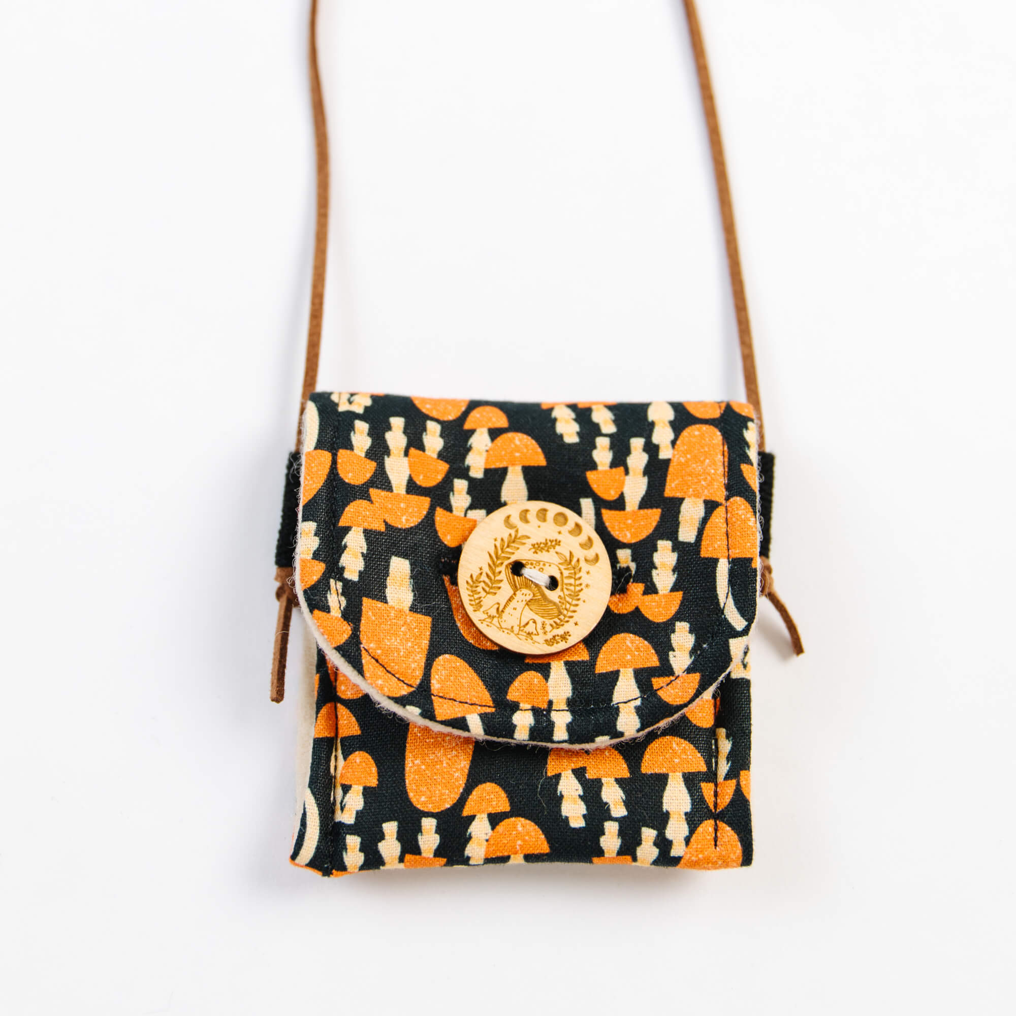 Small bag with mushroom pattern and wooden emblem on a white background