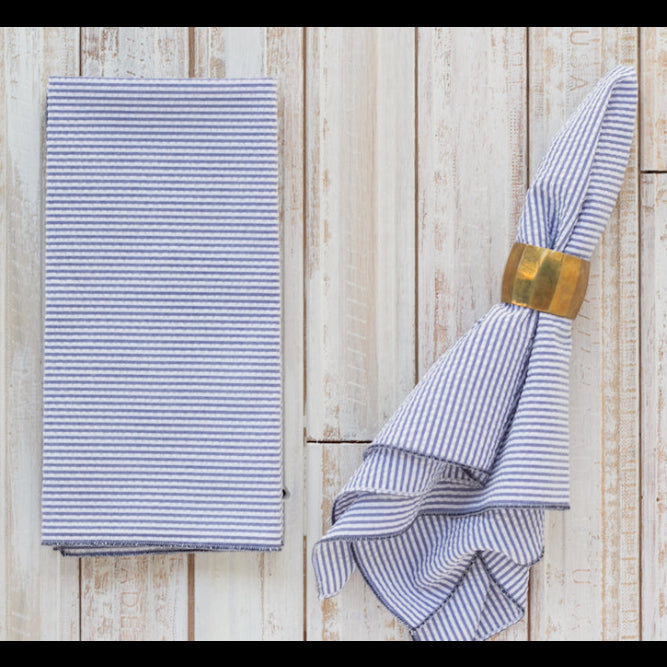 Navy blue seersucker cloth napkins folded and displayed on a wooden table