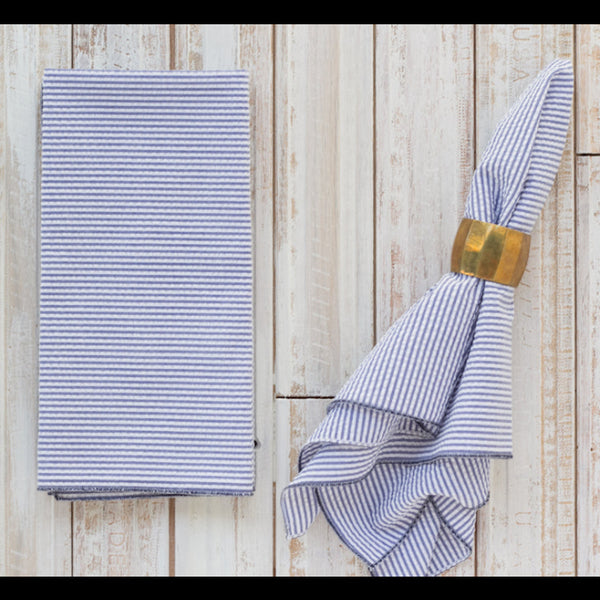 Navy blue seersucker cloth napkins folded and displayed on a wooden table