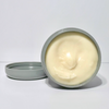 Open jar of cream with a white lid on a light gray background