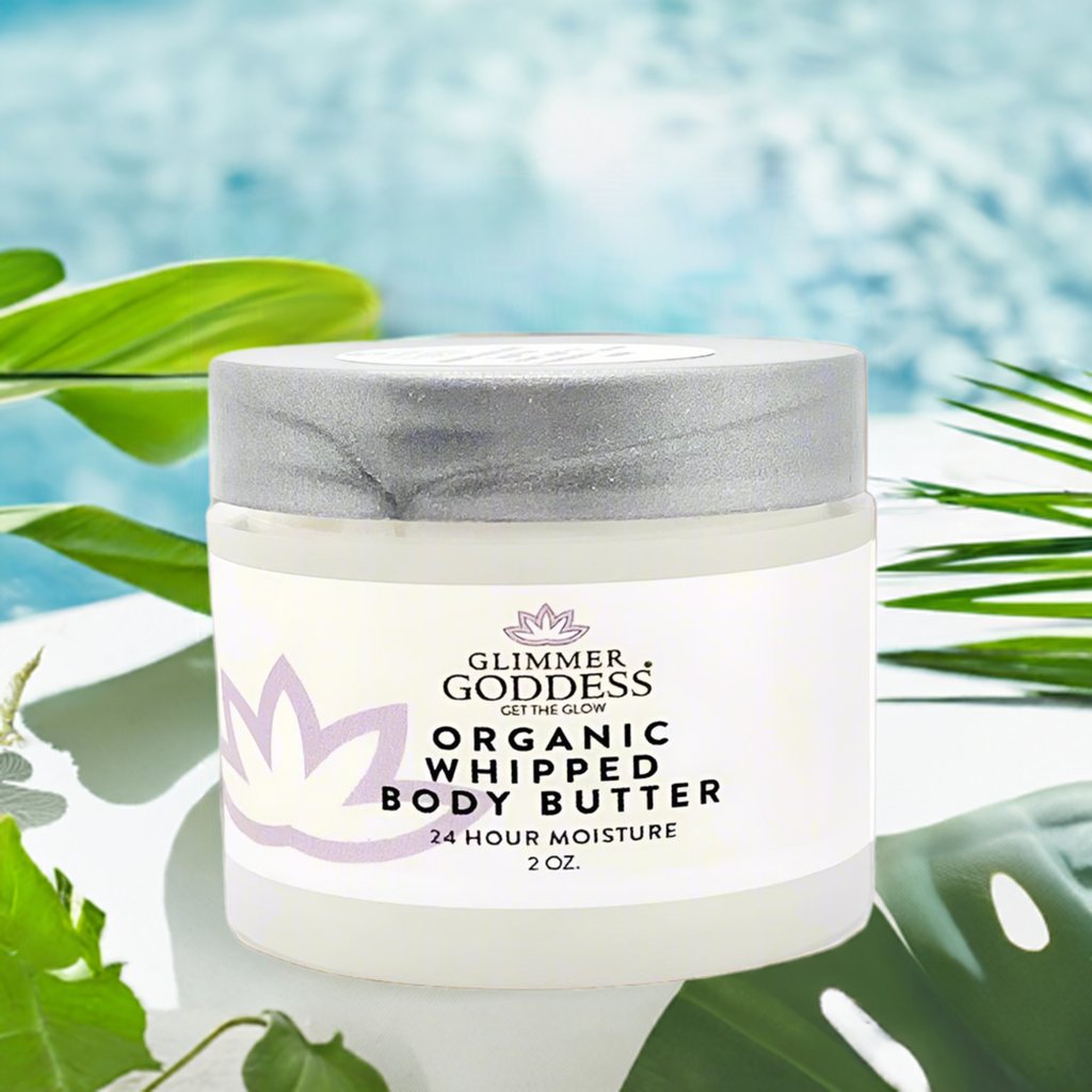 Glimmer Goddess organic whipped body butter jar with green leaves in the background