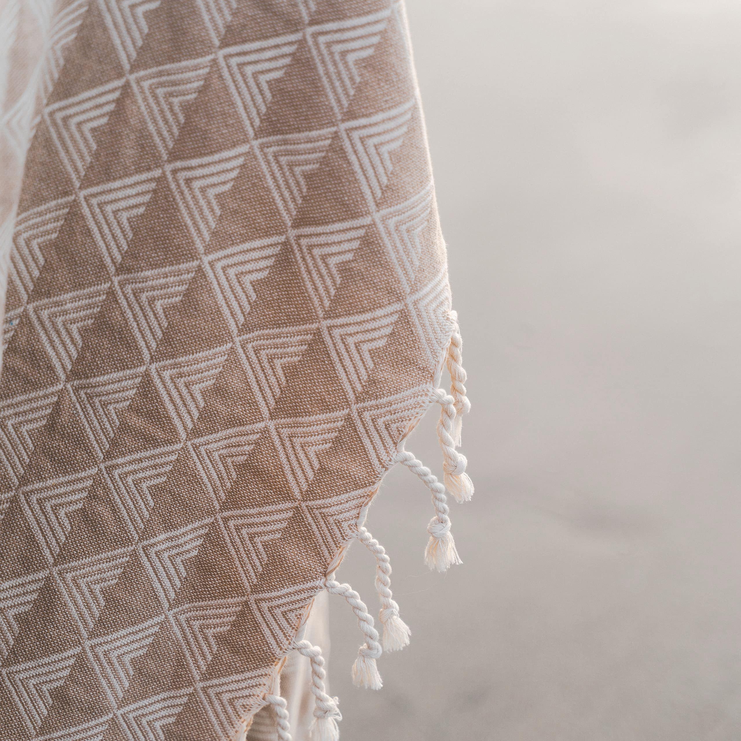 Textured fabric with geometric pattern and tassels on a neutral background