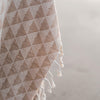 Textured fabric with geometric pattern and tassels on a neutral background