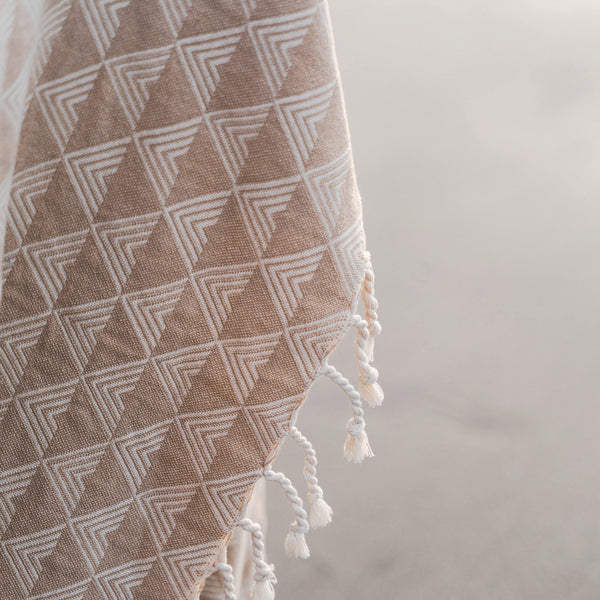 Textured fabric with geometric pattern and tassels on a neutral background