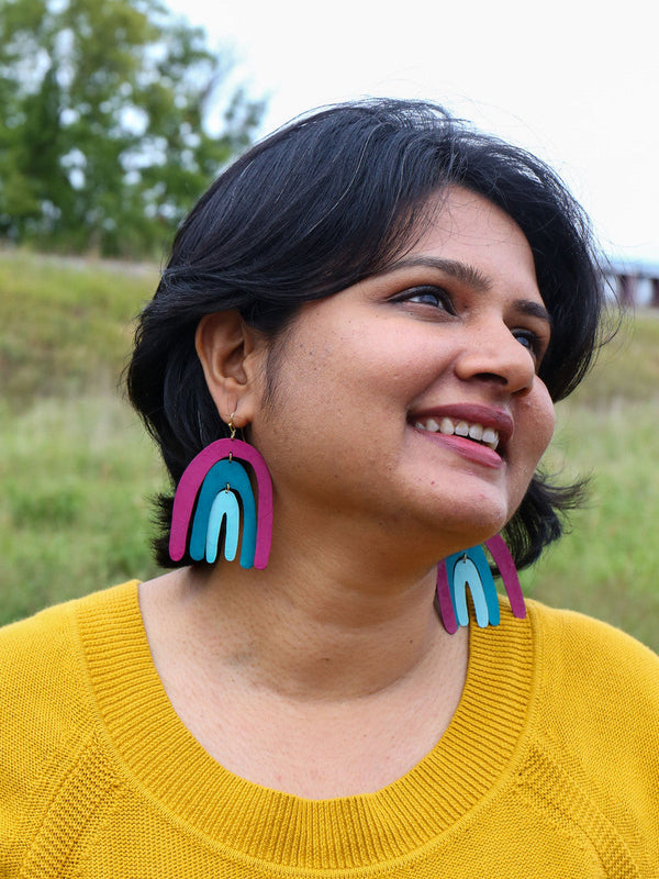 Close-up of hand-painted rainbow dangle earrings in pastel yellow and blue-grey by Fair Anita