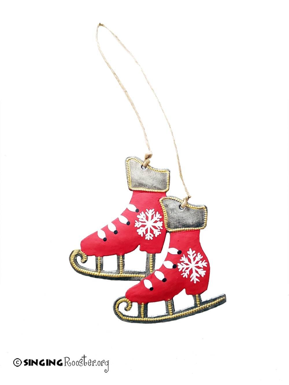 Red ice skate ornament with gold accents and white snowflakes on a white background.
