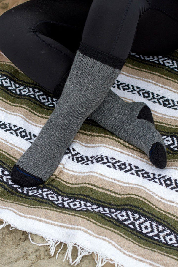 Gray socks worn with black pants on a patterned rug
