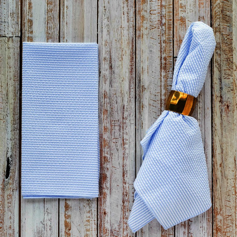 Pale blue seersucker cloth napkins folded and displayed on a wooden table