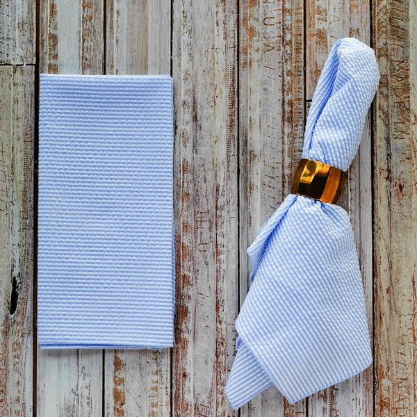 Pale blue seersucker cloth napkins folded and displayed on a wooden table
