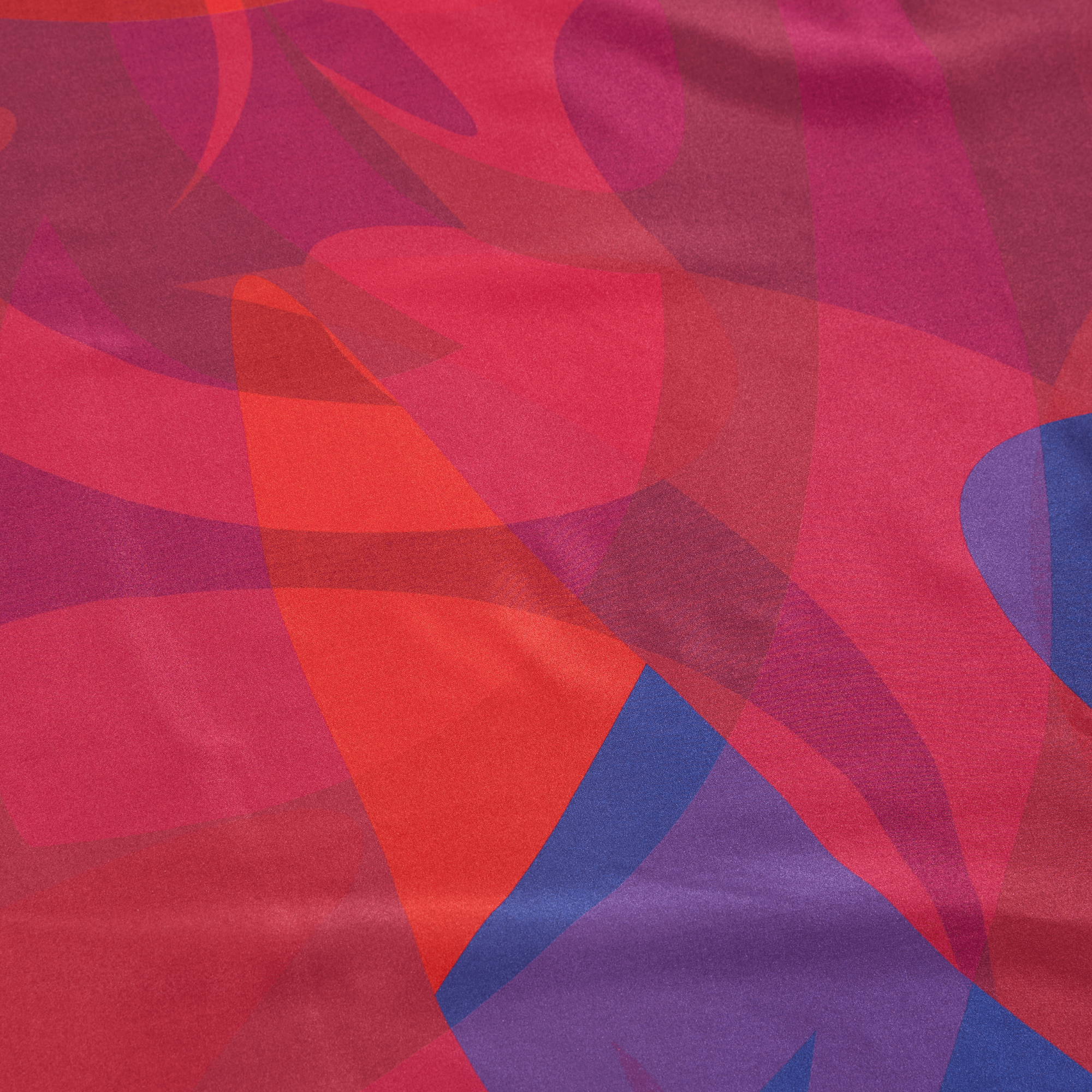 Abstract pattern of red, pink, and blue shapes on a fabric background
