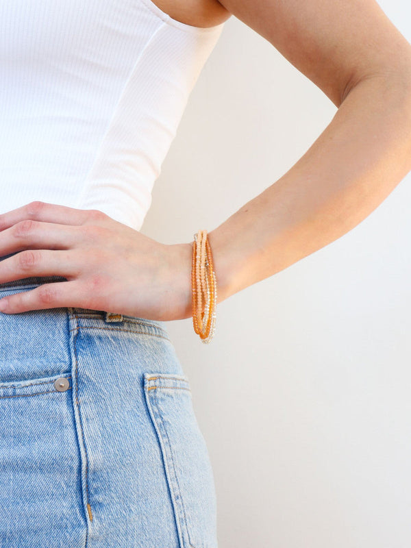 Close-up of peach multistrand sparkly glass bead bracelet by Fair Anita on white background