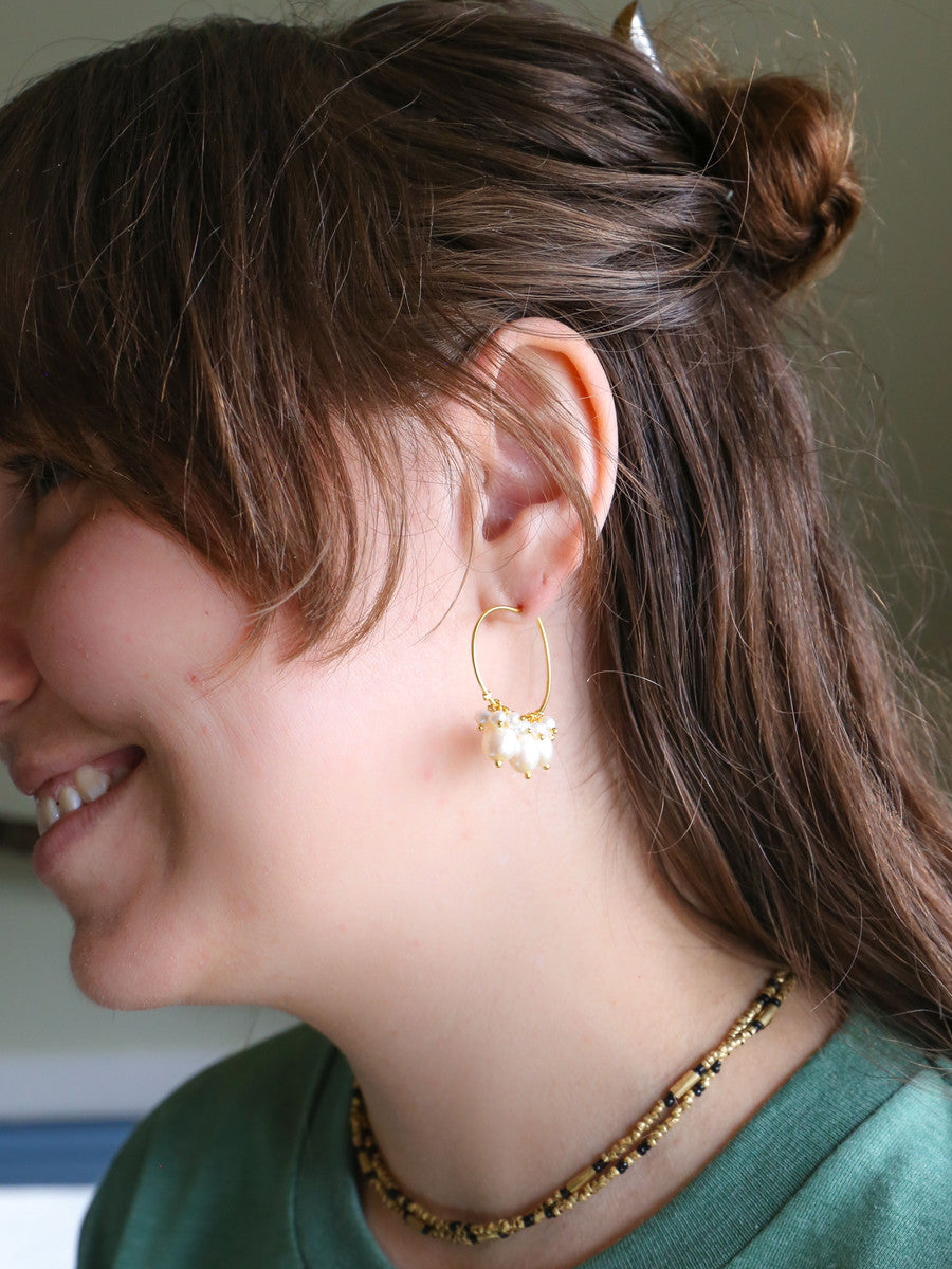 Close-up of pearl cluster hoop earrings by Fair Anita on neutral background