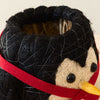 Close-up of a toy penguin with a black hat and red bandana on a neutral background