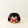 Small plush penguin toy with a red harness on a light background