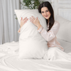 Woman holding a large white pillow in a bedroom setting