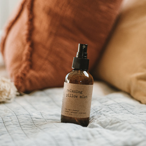 Bottle of 'relaxing pillow mist' on a bed with pillows in the background