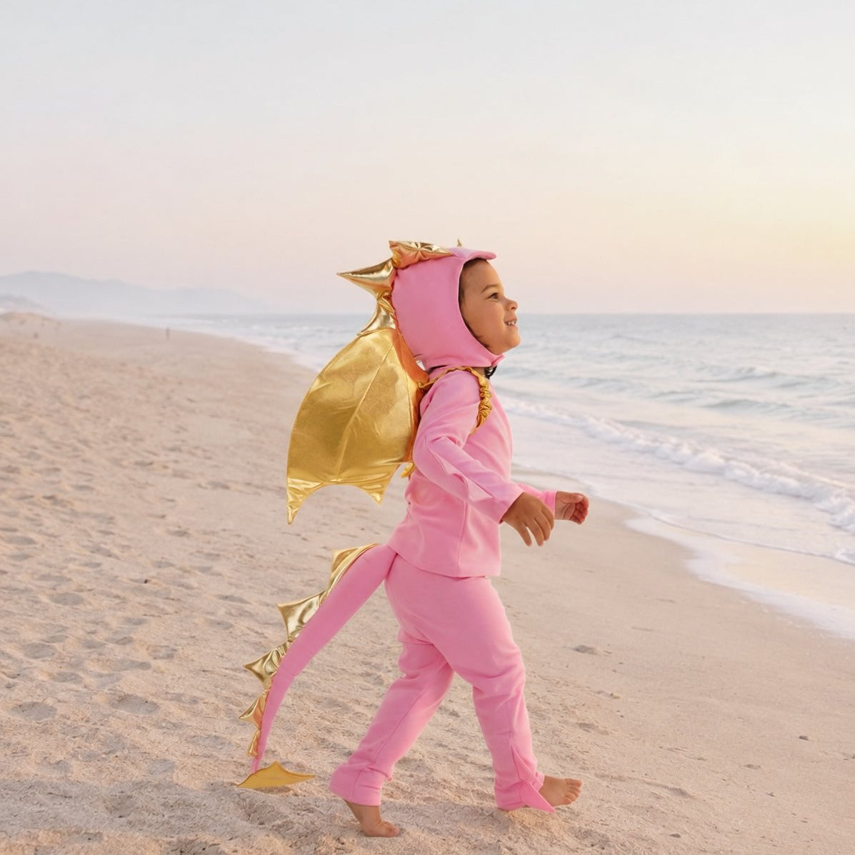 Child wearing the Pink Sky Dragon pajama costume outdoors at the beach