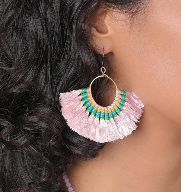 Close-up of a person wearing colorful beaded earrings with pink fringe.