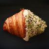 Croissant with white icing and green sprinkles on a black background