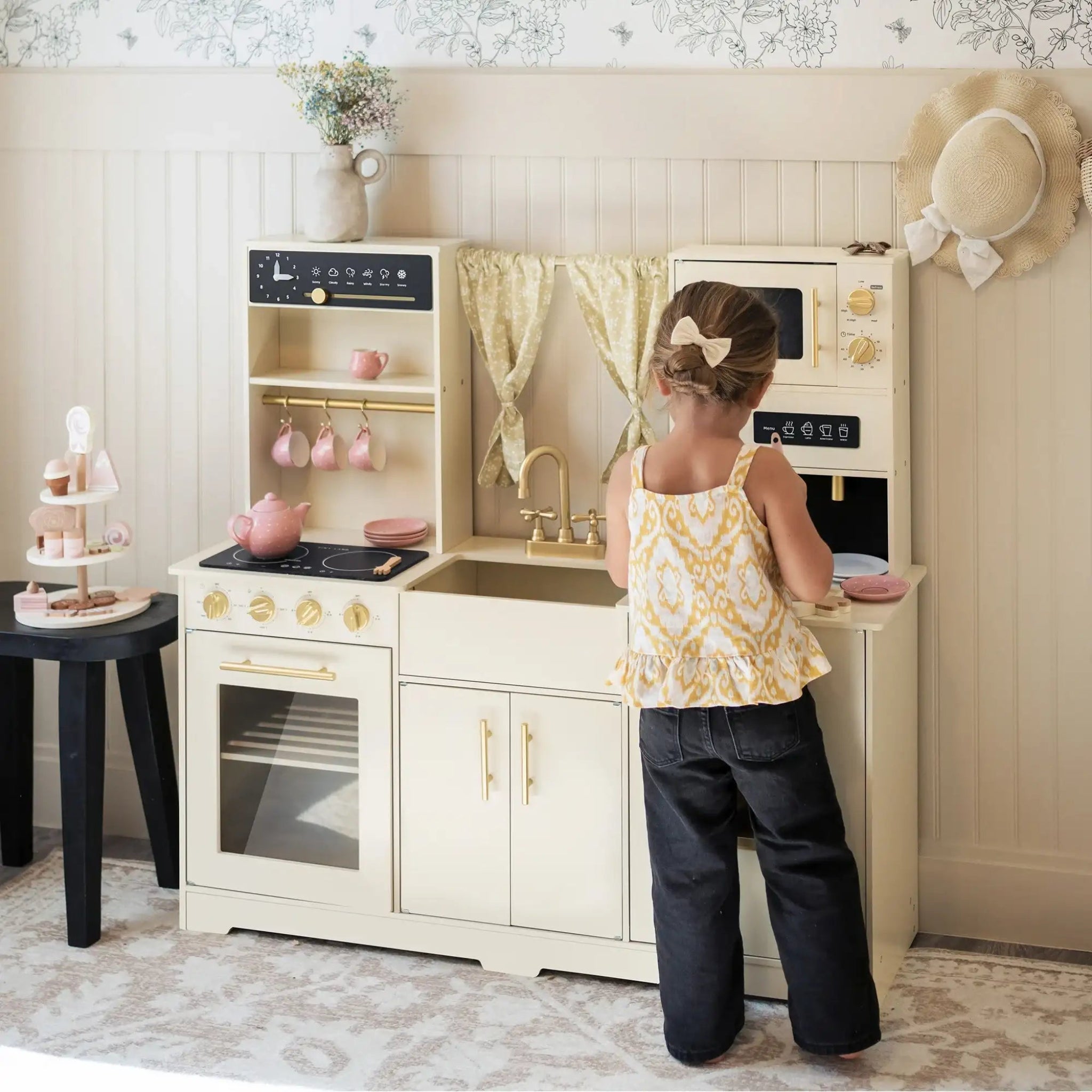 Young child playing with the Tiny Land wooden toy kitchen set featuring oven, microwave and storage