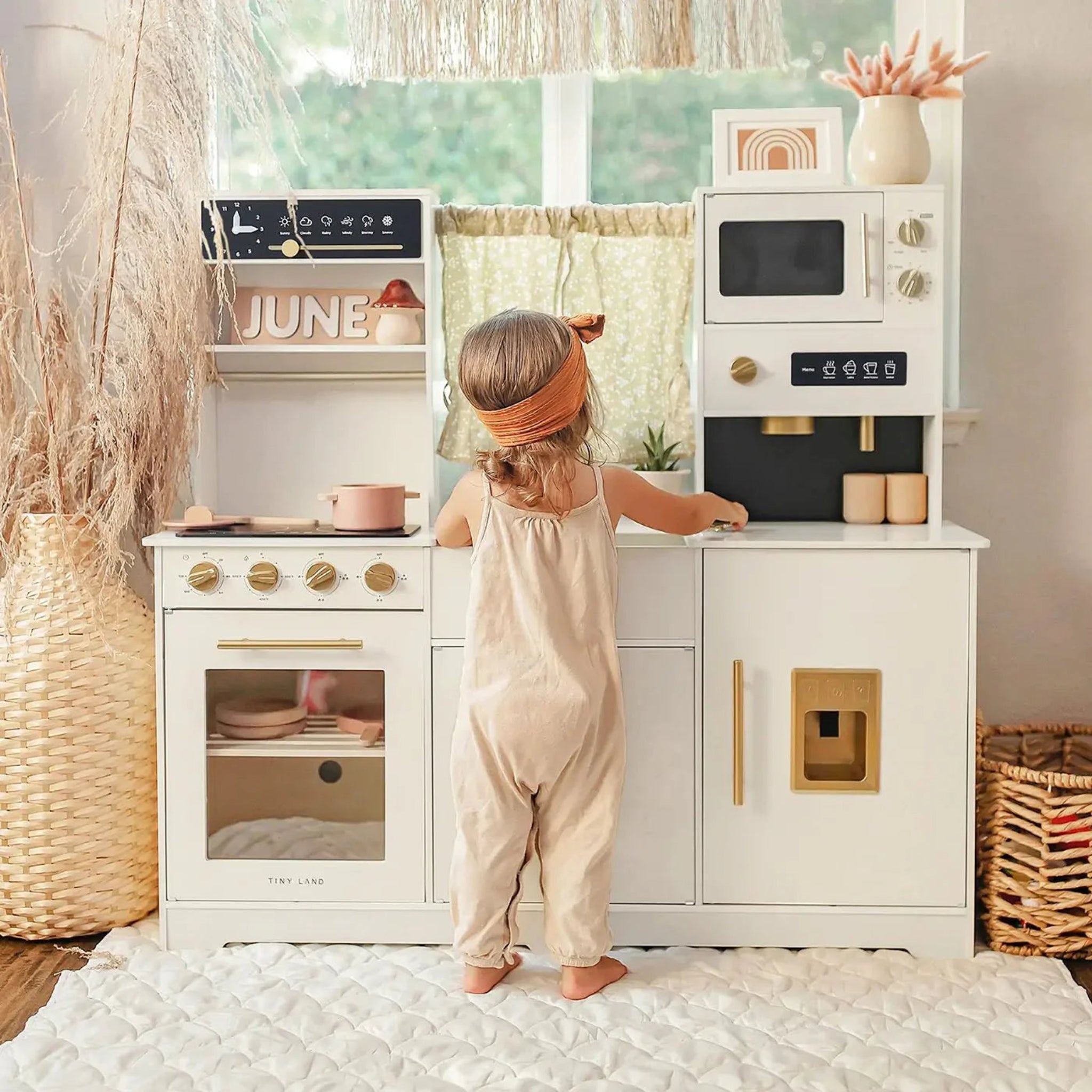 Child using the Tiny Land cream pretend play kitchen in a bright, naturally lit playroom