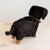 Black yarn-wrapped dog sculpture on a light wooden surface