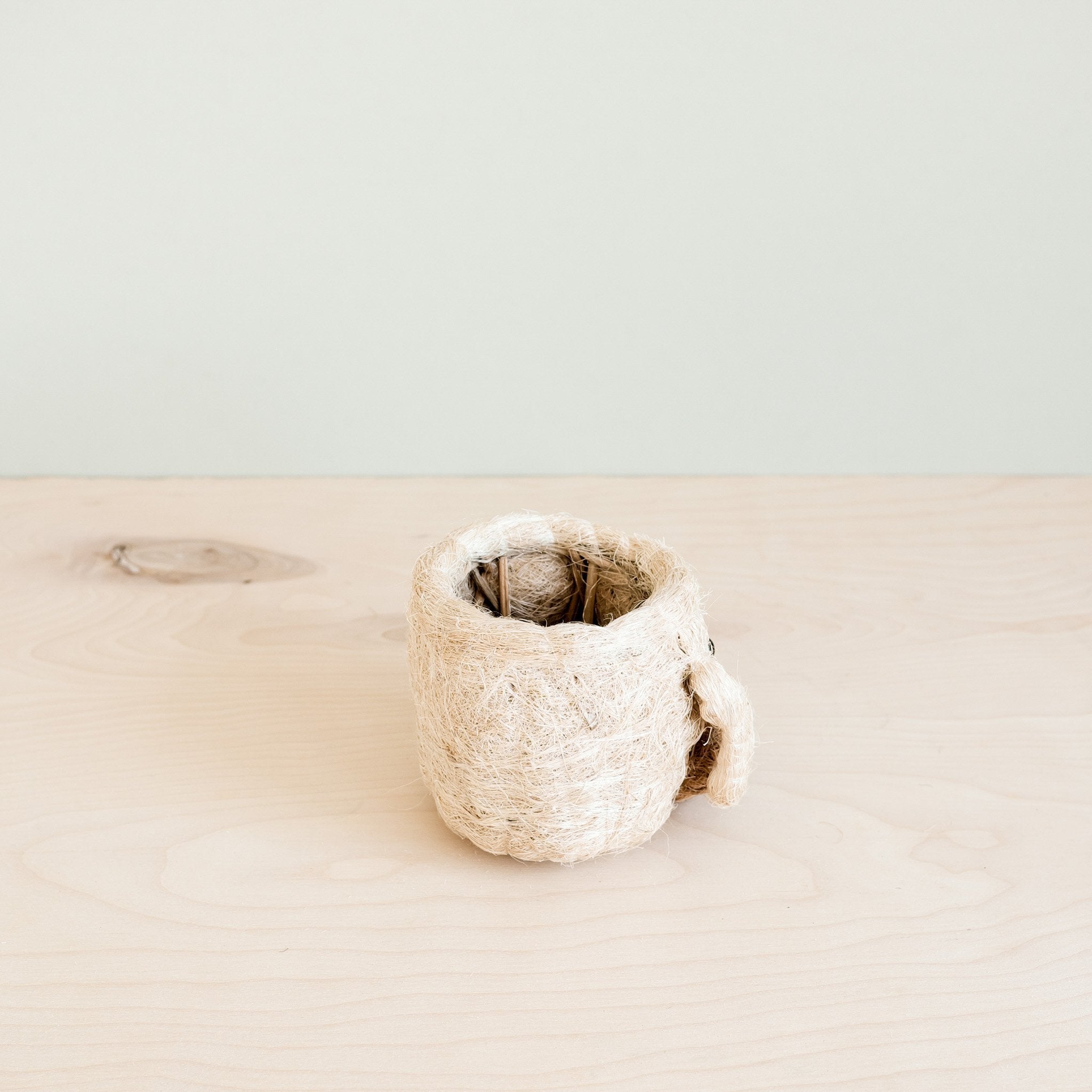 Small woven basket on a light beige surface with a neutral background