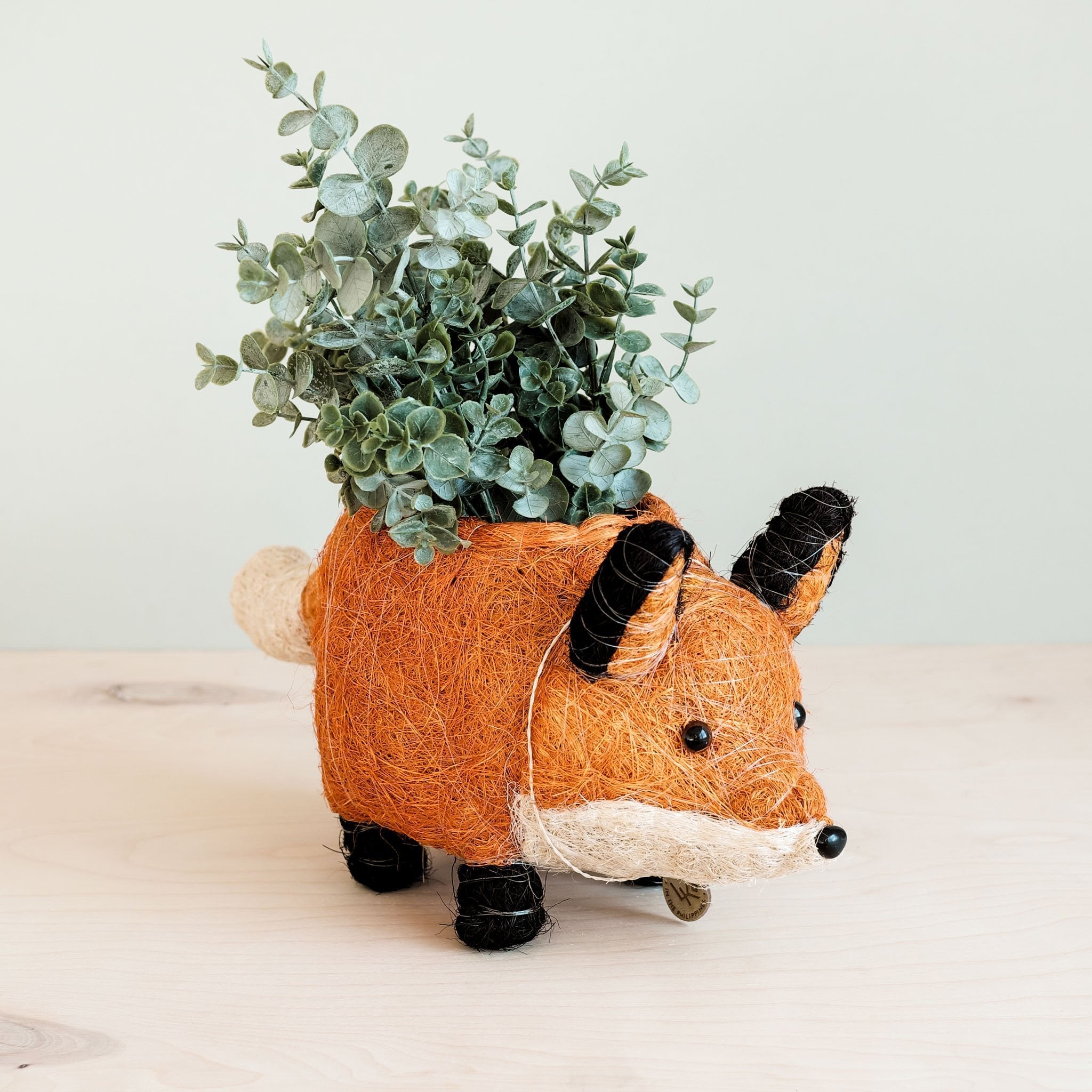 Fox-shaped plant pot with greenery on a light background