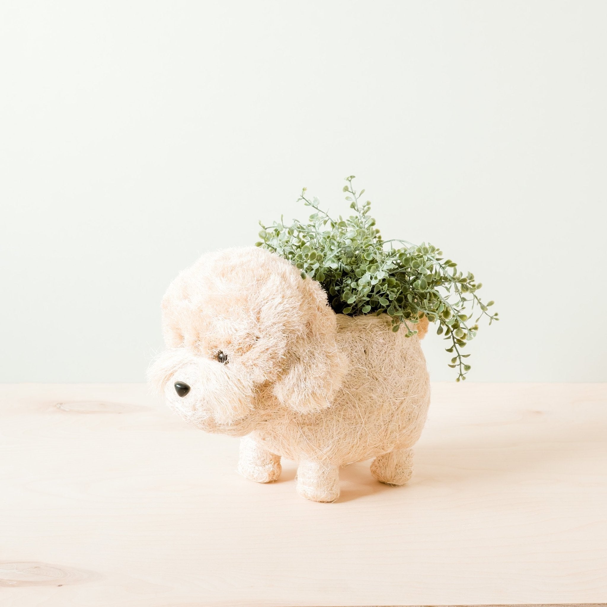 Ceramic dog-shaped planter with greenery on a light background