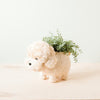 Ceramic dog-shaped planter with greenery on a light background