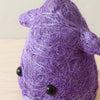 Purple yarn ball with black buttons on a wooden surface