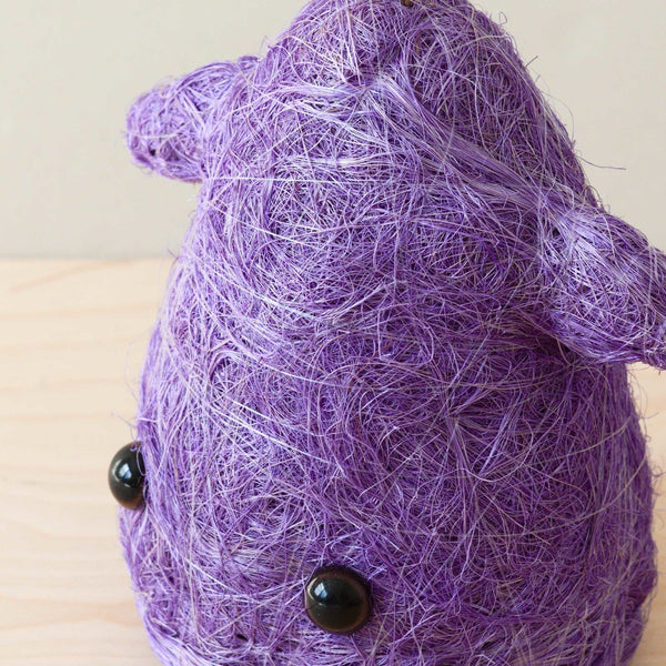 Purple yarn ball with black buttons on a wooden surface