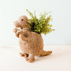Dinosaur-shaped planter with greenery on a white background