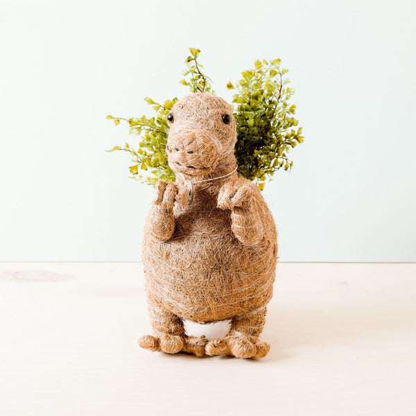 Decorative animal figure wrapped in twine with greenery on a white background