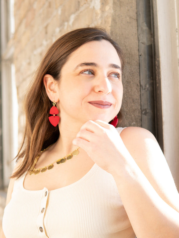 Close-up of red triangle poppy dangle earrings showing upcycled bone material and nickel-free hardware by Fair Anita