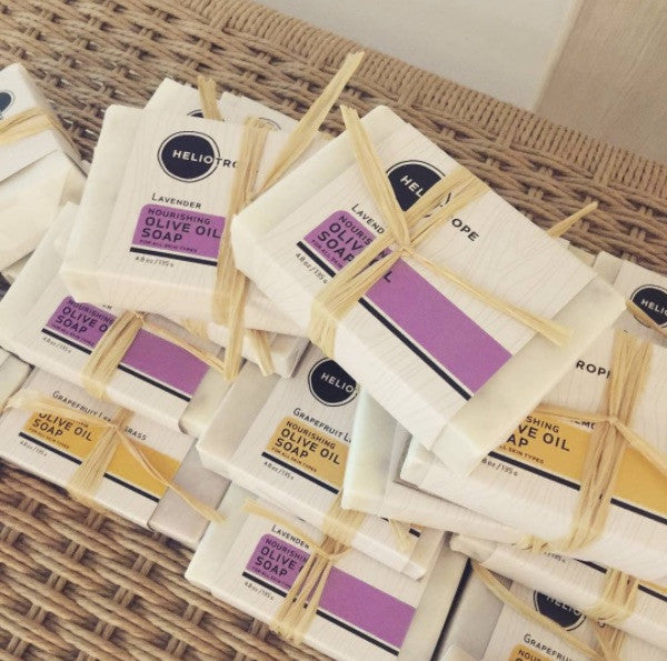 Shea butter olive oil soap bars with Heliconia branding on a woven surface.