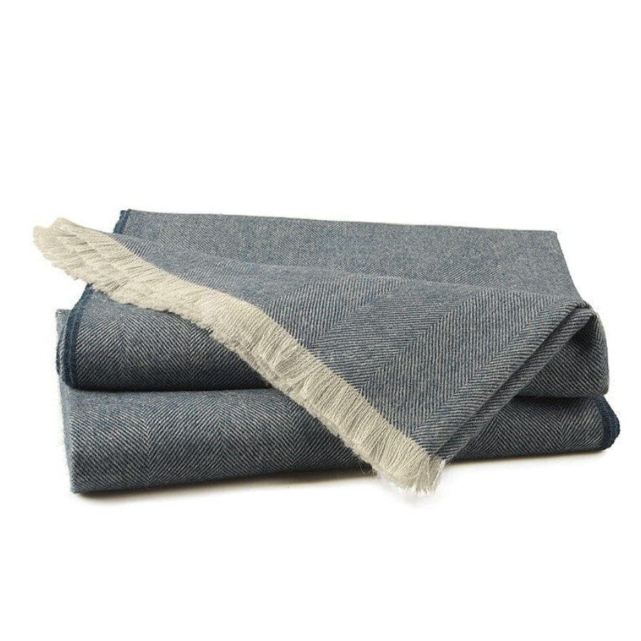 Folded gray blanket with beige fringe on a white background