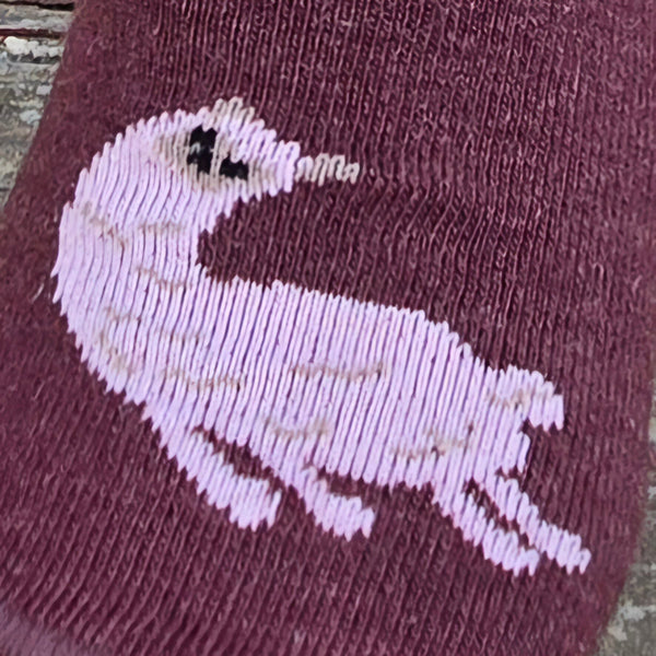 Maroon sock with embroidered white duck design on a textured surface. Discover our fun Pronk & Play Alpaca Socks, featuring a cheerful design for adults and kids. Made with a soft alpaca blend, these USA-designed socks are comfortable and durable. Shop now and add a little joy to your step.