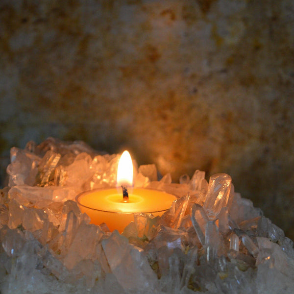 Candle in a crystal holder with a warm glow against a blurred natural background