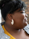 Overhead flat lay of Fair Anita raffia hoop earrings on neutral background